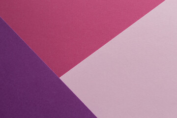 Pink, burgundy and purple paper lie on the table in a geometric composition