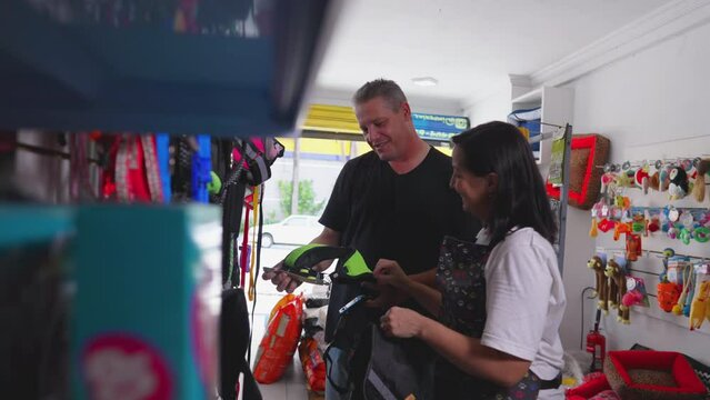 Male customer Shopping at Pet Shop: Female Business Owner Assisting in Dog Item Selection inside local store