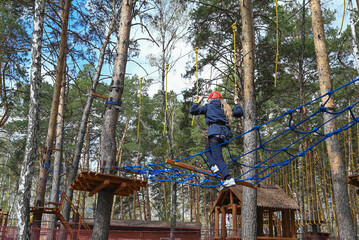a teenage girl passes an obstacle in a rope park