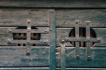 Close-up of an old wooden door with a pair of small windows closed by rusty metal grates, Venice, Veneto, Italy