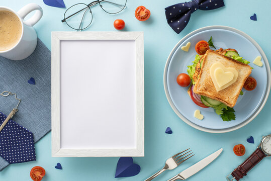Make Dad feel special with a surprise breakfast on Father's Day. Top view of a photo frame, homemade breakfast, men's accessories, on a pastel blue background with an empty frame for text or advert