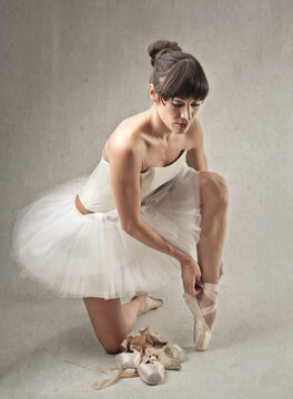 classical dancer puts on her ballet shoes