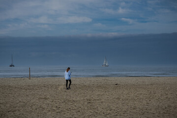 Woman walking on a sandy beach of Viareggio in winter, Italy 