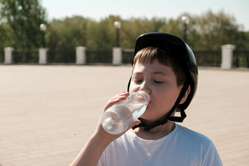 portrait of cute boy in helmet is drinking water in bottle in sakatepark.