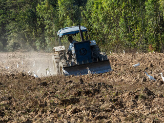 The farmer drives the tractor to adjust the soil.