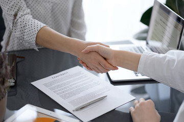 Business people shaking hands above contract papers just signed on the white table, closeup. Lawyers at meeting. Teamwork, partnership, success concept - 602097931