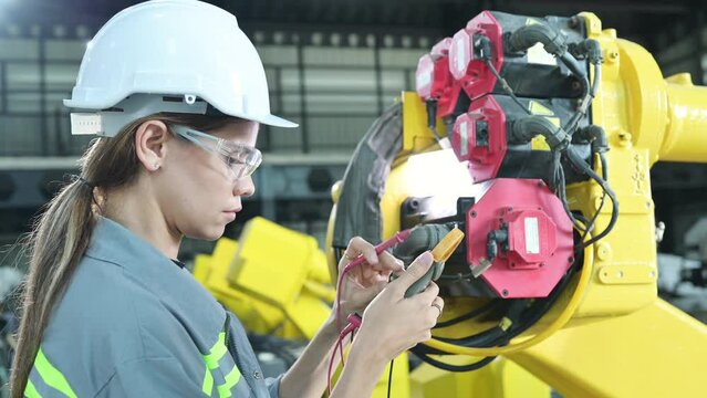 In the robots warehouse, A female engineer inspects the electrical system of every robotics arm, before delivering to the customer.