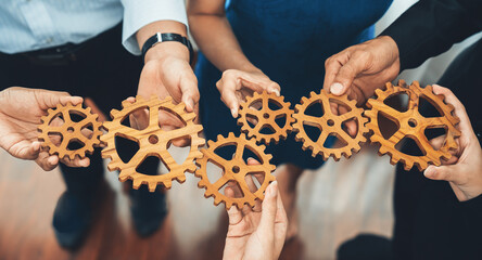 Office worker holding cog wheel as unity and teamwork in corporate workplace concept. Diverse...