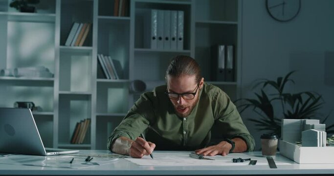 Portrait of an enthusiastic architect working hard on blueprints.