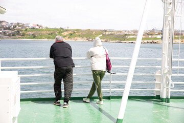 Fototapeta na wymiar a couple of man and woman stand on a ferry boat trip by sea