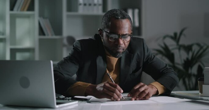 Portrait of an african american male architect attentively drawing blueprints
