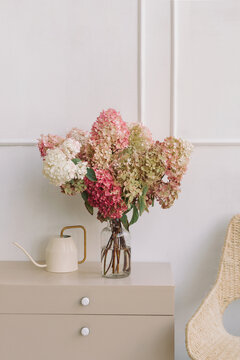 Vase of hydrangea flowers on a sideboard with a watering can