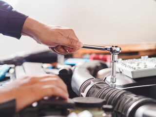 Hands of car mechanic with wrench in garage. Close up hands of unrecognizable mechanic doing car service and maintenance. Auto Service Business Concept. Pro Car Mechanic Taking Care of Vehicle.