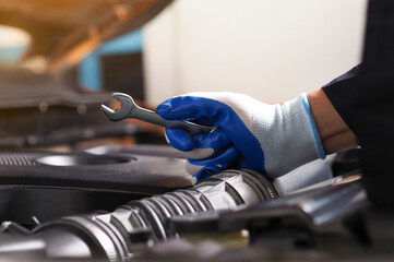 Hands of a car mechanic with a wrench. Mechanic repairing the engine of a car in the garage Repair and maintenance. Auto mechanic working on car engine in mechanics garage.