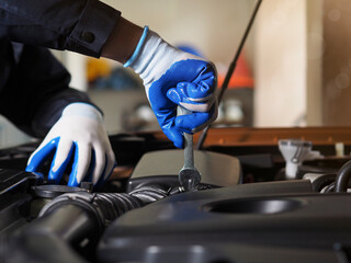 Hands of a car mechanic with a wrench. Mechanic repairing the engine of a car in the garage Repair and maintenance. Auto mechanic working on car engine in mechanics garage.