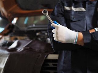 Obraz premium Auto mechanic working on car engine in mechanics garage. Hands of a car mechanic with a wrench. Mechanic repairing the engine of a car in the garage Repair and maintenance.