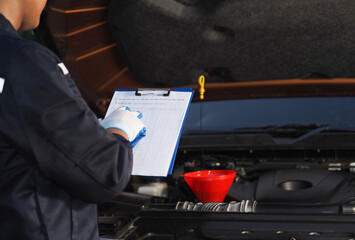 Car repair oil level checking concept in auto service, auto mechanic checking car engine with check...
