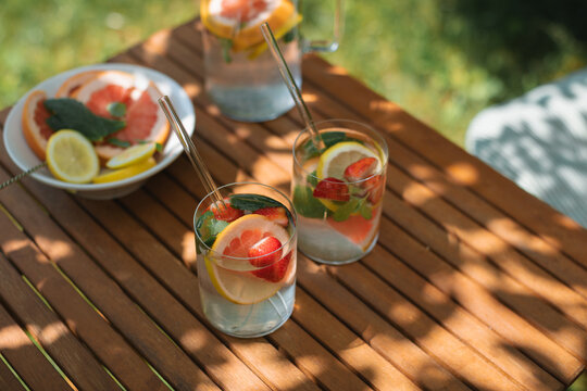 Close-up of two summer drinks with fresh fruit on a table in dappled light