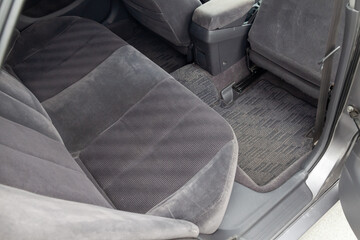 Close-up on rear seats with velours fabric upholstery in the interior of an old car in gray after dry cleaning. Auto service industry
