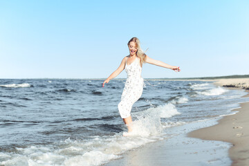 Fototapeta premium Happy blonde woman in free happiness bliss on ocean beach standing straight and posing