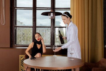 A famous businesswoman or celebrity in a black dress and headscarf, accompanied by her assistant or...
