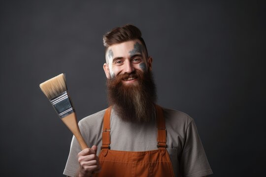 Smiling bearded young hipster painter in the workwear with a paintbrush in his hand. AI generative
