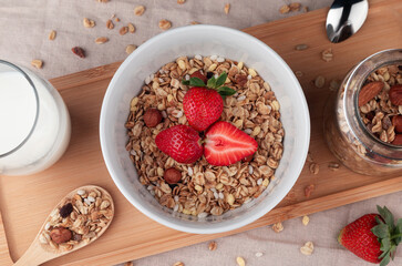 Granola cereal with strawberry , nuts, milk and banana in bowl on a table. Healthy cereal breakfast. Top view.