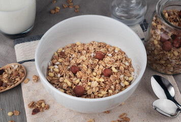 Crispy granola with nuts in bowl on light table background. Healthy cereal breakfast. Top view.