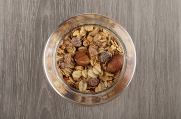 Homemade granola in jar on kitchen table, healthy breakfast of oatmeal muesli, nuts, seeds and dried fruit.
