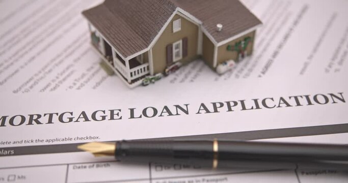 Mortgage loan or home equity loan, financial concept : Model residential house, a pen on mortgage application, depicting home loan or borrowing money to purchase a new home for first time homebuyer.