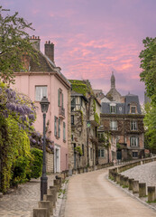 Montmartre Paris France. Maison Rose and cobbled street leading uptown Montmartre at sunrise with a pink sky. Tourism in central Paris, Europe. 