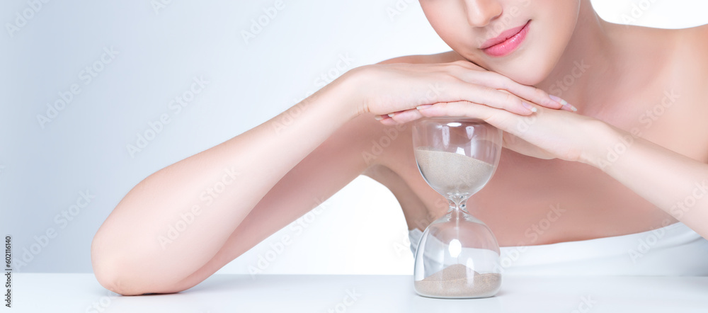 Wall mural closeup personable model holding hourglass in beauty concept of anti-aging skincare treatment. young