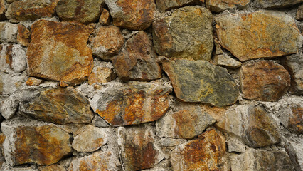 Aged masonry rock wall texture, brown rock, rock wall surface. Texture of the ancient dilapidated wall fencing in the old town. Stone wall background, front view