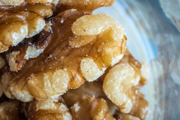 Peeled walnut halves inside glass jar closeup