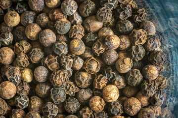 Dry black pepper inside glass jar closeup