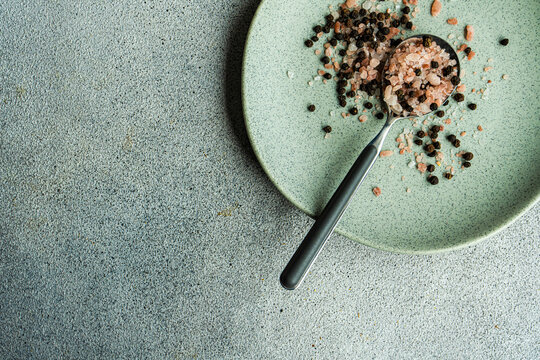Close-up of a spoonful of mixed peppercorns and pink Himalayan rosemary and lemon salt on a plate