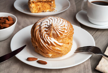 Almond profiterole cake on a plate with coffee.  - obrazy, fototapety, plakaty