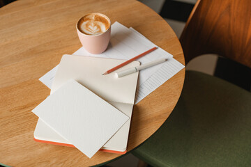 Overhead view of a cappuccino and a glass of water on a table with a blank notepad