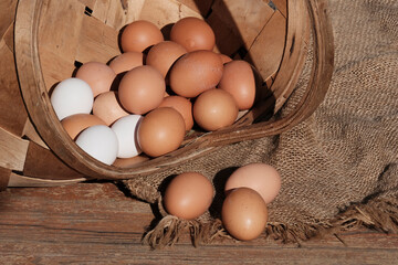 Beautiful brown colored eggs in a wooden basket in sunlight. Farmer's market, Egg price, increase. dietary product. Beautiful background with eggs.