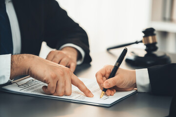 Lawyer signing contract, professional lawyer in law firm library drafting legal document or...