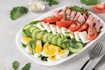 Healthy cobb salad with ham, feta cheese, cucumber, tomato, olives and eggs. Ketogenic lunch
