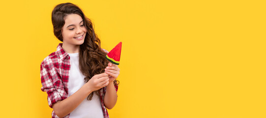 smiling teen girl with long curly hair in checkered shirt hold lollipop caramel candy, candy treat. Teenager child with sweets, poster banner header, copy space.