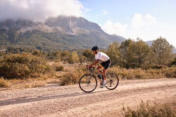 Cyclist practicing on gravel road.Fit male cyclist riding a gravel bike on a gravel road with a...
