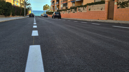 Level asphalted road with a dividing white stripes. The texture of the tarmac, top view. High quality photo