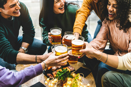 Group of multiracial friends drinking and toast beer at brewery pub enjoying happy hours-Young diverse people having fun at bar during summer party -Youth culture-Life style Food and beverage concept 