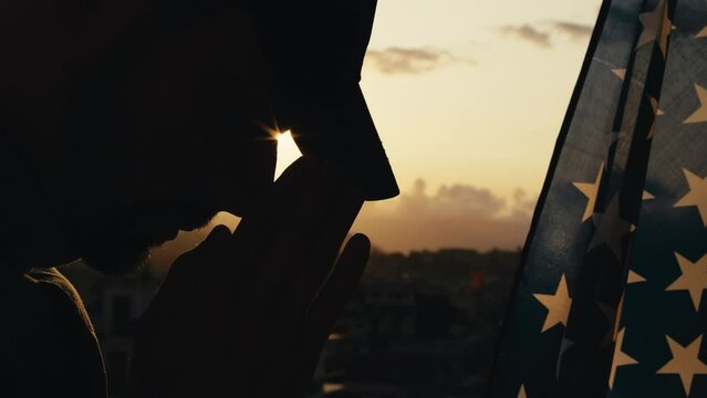 Soldier Praying for memorial day war dead against sunset and american flag