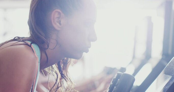 Tired, cycling and face of woman at gym for fitness workout, weight loss or endurance training. Breathing, sweat and fatigue with real girl in spin class for sports, health and cardio challenge