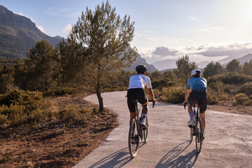 Fototapeta premium Men cyclists riding a gravel bicycles on the road in hills with mountain view, Alicante region in Spain.