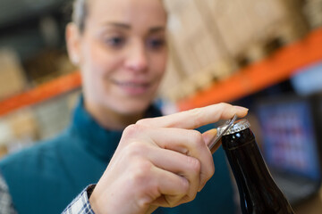 female worker opening a beer bottle with a bottle opener