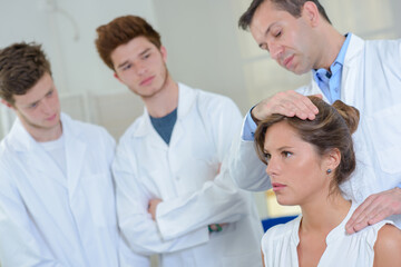 Obraz premium Students observing doctor with hand on patient's head and shoulder